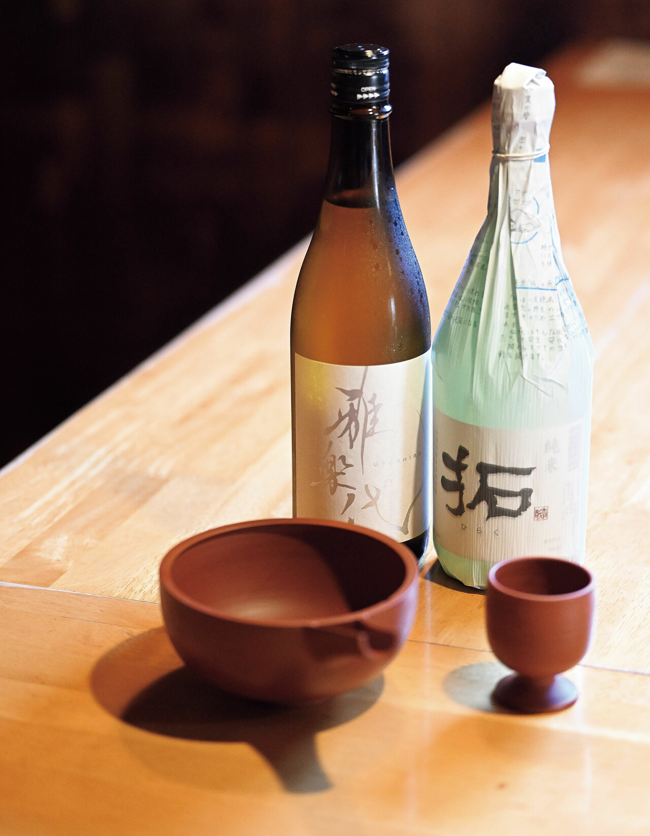 左から天領盃酒造の雅楽代（うたしろ）と金鶴などを醸造する加藤酒造店の純米 拓（ひらく）。佐渡の地酒を各種常備。日本酒の他にもトキブルワリーのクラフトビールや赤ワインも。焼鳥とのマリアージュを楽しんで。