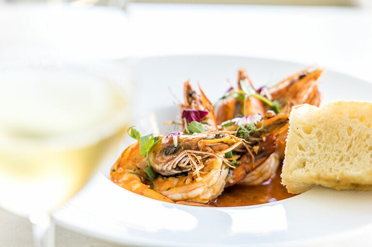 オープンエアの空間も用意するレストラン「キオラ」で上質なイタリア料理を。“カウアイ産エビのカラブレーゼ” 25ドル。