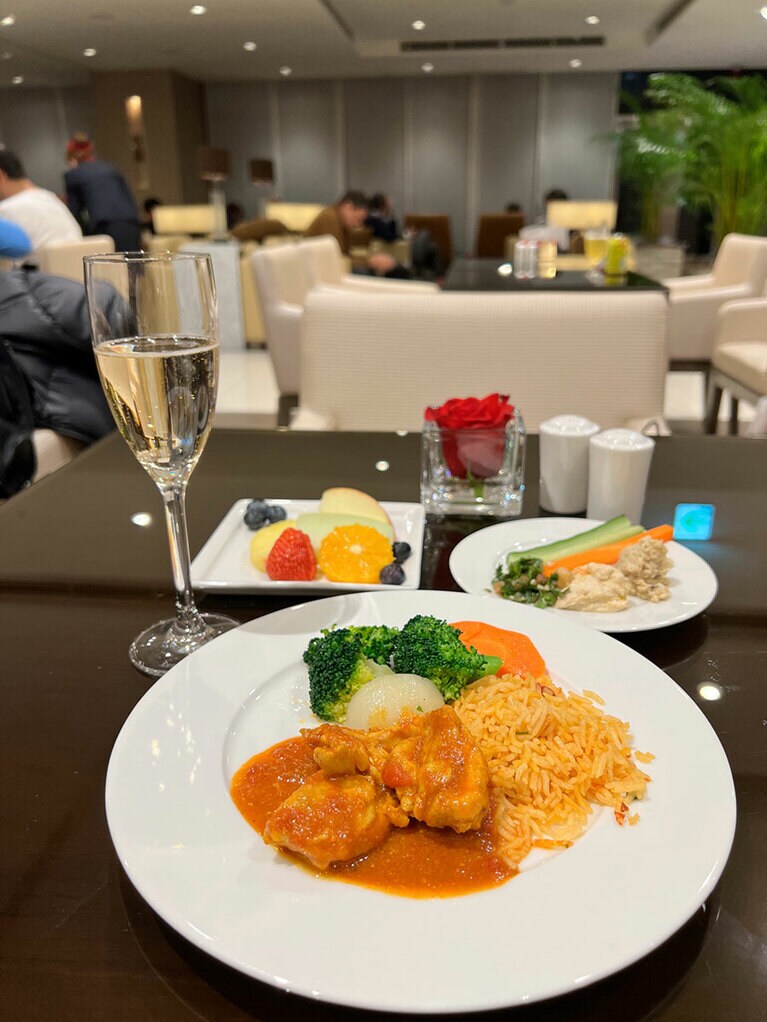 手前がチキンのマチュブース。スパイスとチキンスープで炊き込んだご飯とともにいただく。右奥のお皿にはフムス（ヒヨコ豆のペースト）とムタッバル（ナスのペースト）。テーブルに置かれたバラもコーポレートカラーの赤。