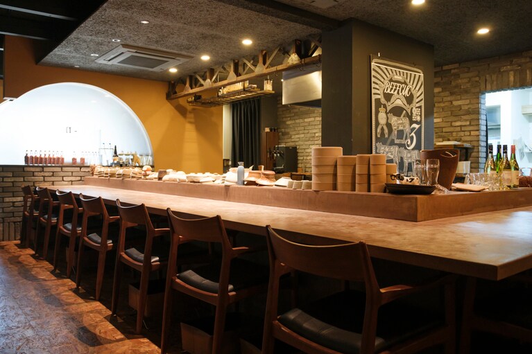 オープンキッチンを囲むカウンター席、テーブル、半個室で構成。