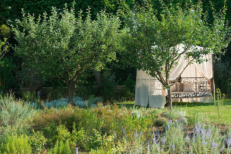 庭園にはモロッコ風の天蓋付きデイベッドも。バラやハーブの香りに包まれてまどろみたい。