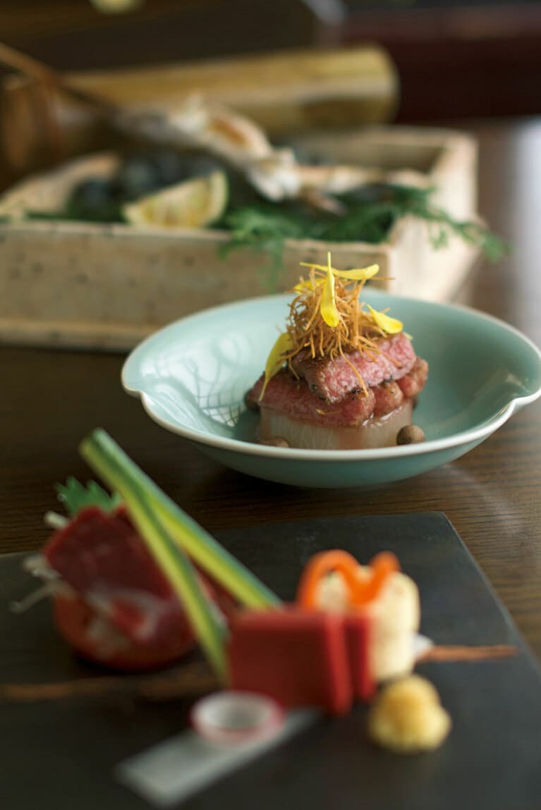 【旅館 山河】名物の3品。手前から馬刺、阿蘇あか牛ステーキ、山女魚塩焼き。ステーキの下は特産の小国大根。上には細く切って揚げた“髭牛蒡”と菊花をのせ、周りに零余子を散らして。／Photographs：Hiroshi Mizusaki