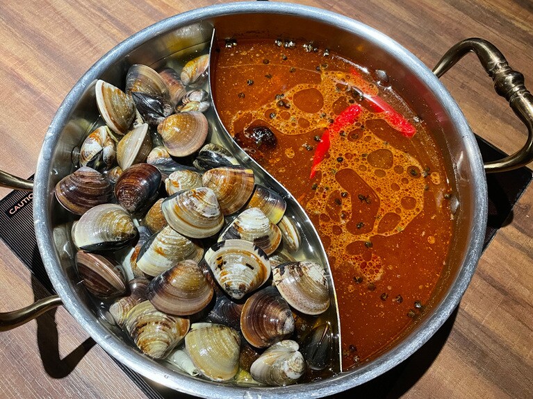 大量のアサリが入った鍋と、伝統的な麻辣火鍋に、日本のエッセンスを加えたオリジナルスープの組み合わせ。