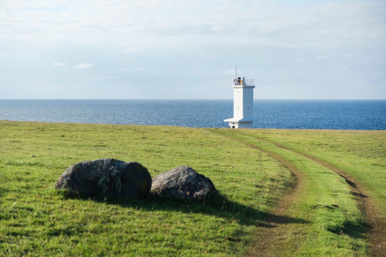 斑島灯台（長崎県五島列島）。⼩値賀⽕⼭島群である斑島の北西部、牛の放牧場となっている岬「ト子リノ鼻」に立つ。黒い玄武岩に白い外観が映える、高さ10mほどの灯台。