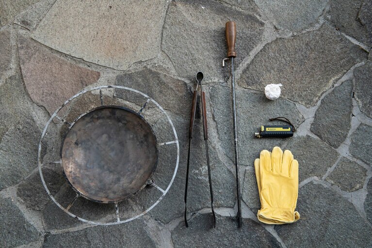 左から、焚き火台、火ばさみ、火吹き棒、植物由来の燃焼補助剤(白い包み)、ライター、グローブ。