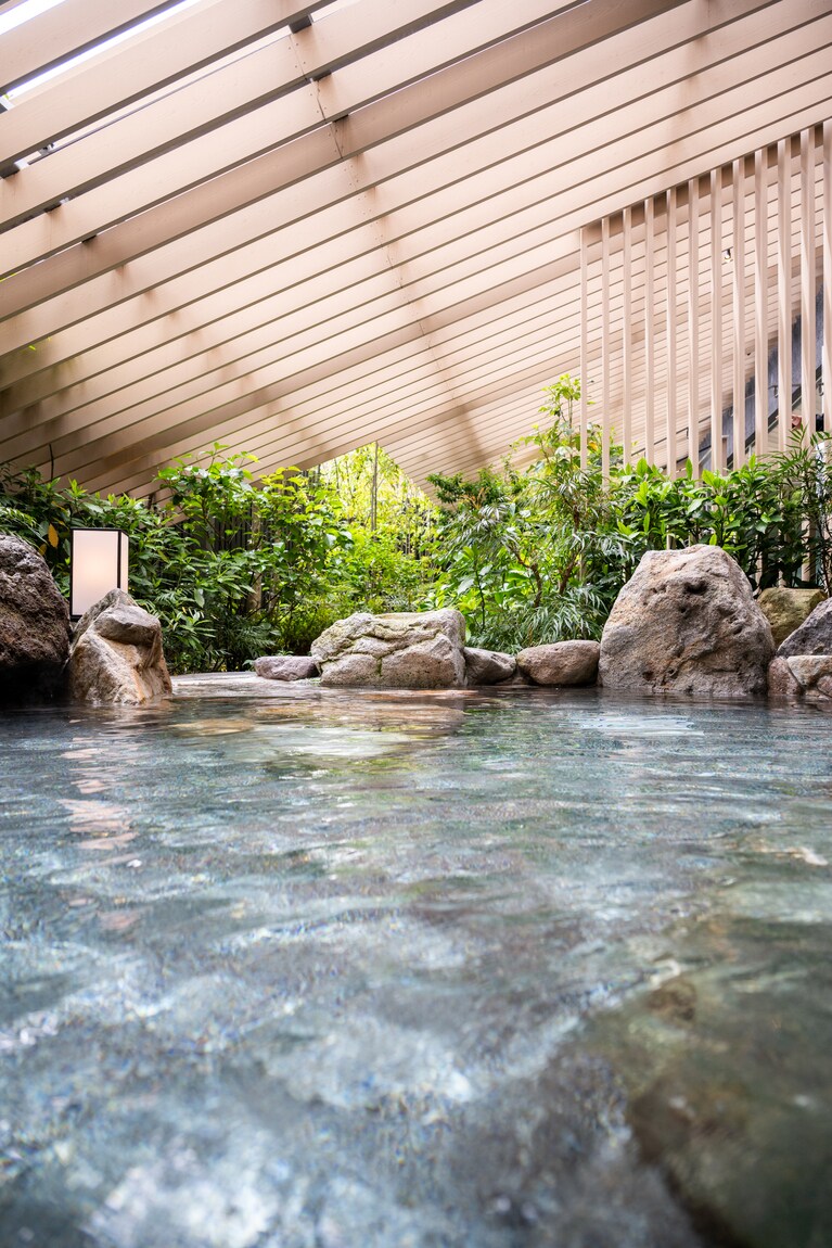 庇の下に別府石を配した温泉大浴場の露天風呂。