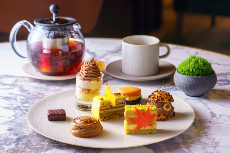 「ピエール・エルメ・パリ」の芸術的なスイーツのイメージ。フランボワーズとイチジクのコンポートを重ねたケーキ「イビサ」は、紅葉を象ったチョコレートを添えて、秋の情景を華やかに表現した特別仕様で供される。