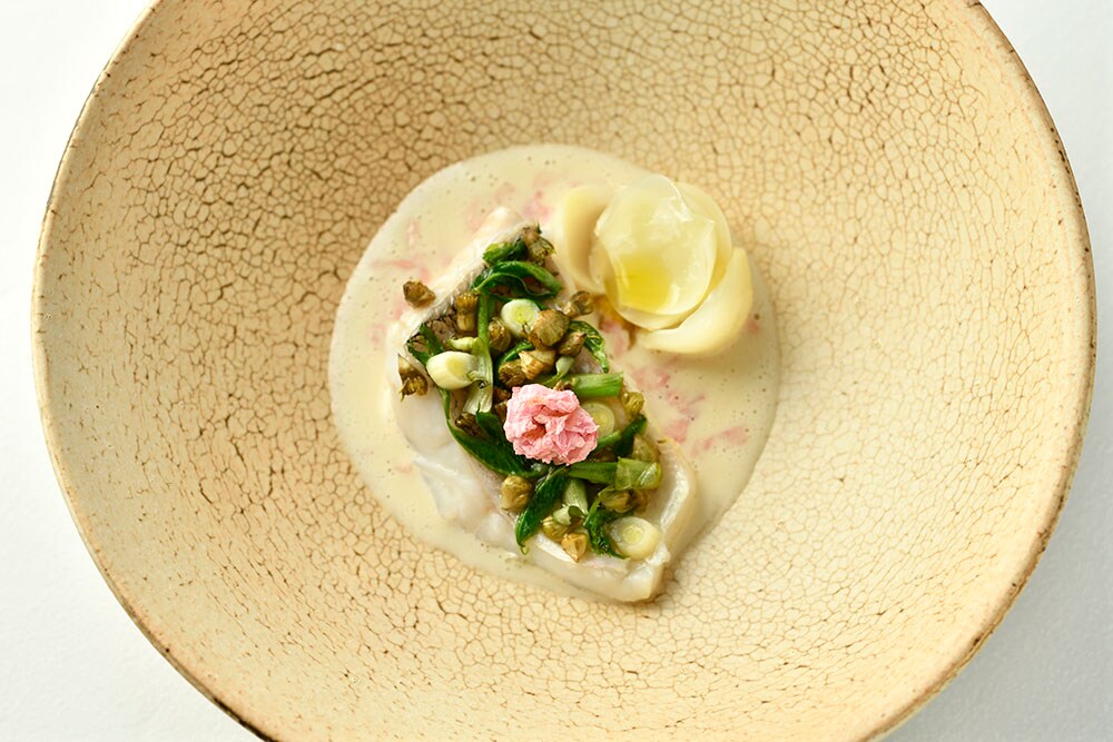 京都で提供される料理の一例。旨みののった甘鯛を繊細な白ワインソースで味わう一皿。塩漬けの花びらが華やかなアクセントに。