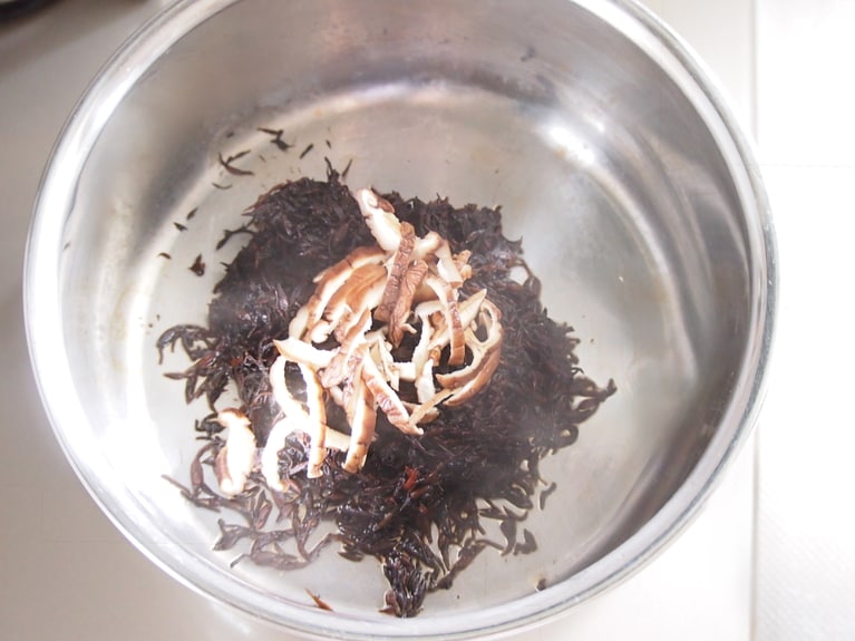 鍋にごま油、水切りした（2）のひじきを入れる。（2）の椎茸を千切りにして加え、混ぜながら加熱する。