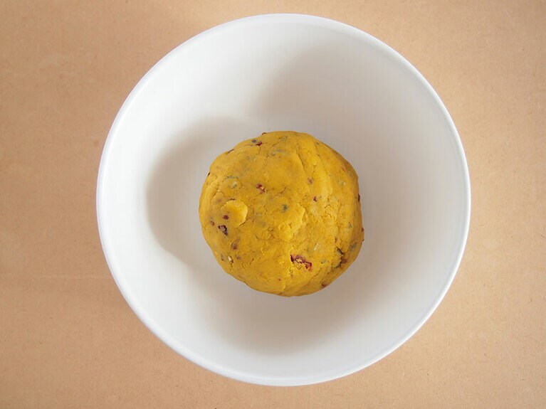 (4) 手でまとめるようにしながら、ボール状に生地を丸めます。かぼちゃの水分量が少ないときには、まとめにくくなることもあります。その場合は、水を少量足しながら生地同士をくっつけていきましょう。