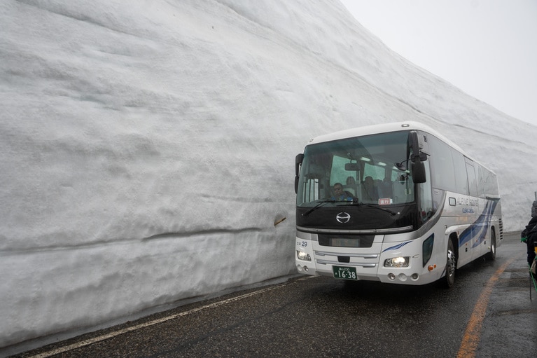 バスよりも優に高い雪の壁。片側がバス、もう片側がウォーキングゾーンに分かれています。