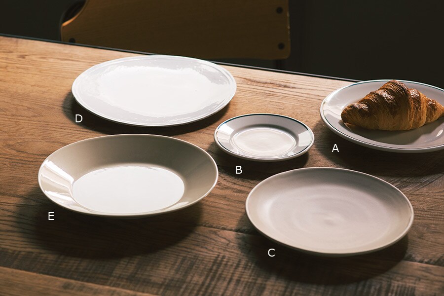 A・B. 業務用の皿としてスペイン国内で広く愛用される。プレート(φ23㎝) 1,800円、(φ18㎝) 1,300円／ポルバサル(ザッカワークス)
C. 手仕事によって一点一点丁寧に仕上げられたぬくもり感が漂う逸品。プレート 13,500円／クリスチャンヌ・ペロション(ドワネル)
D. 食卓にニュアンスを生むハンドメイドの白い陶器。プレート 10,200円／アスティエ・ド・ヴィラット(エイチ・ピー ・デコ)
E. カイピアイネンがデザインしたEEVAオーバルプレートをスコープが復刻！　さり気ないオーバルフォルム。プレート 5,400円／アラビア(スコープ)