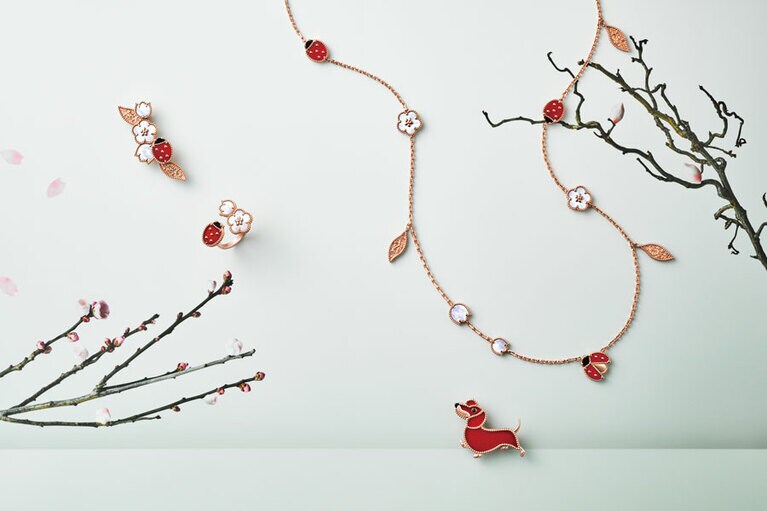 左：曇りなき反射光を放つ虹色のマザーオブパールと、透明度や均一な色調が見事なカーネリアン。選び抜かれたオーナメンタルストーンの競演が春を彩る。幸運を引き寄せるてんとう虫は、1960年代から続くメゾンを代表するラッキーモチーフの一つ。「ラッキー スプリング」（RG、オニキス、カーネリアン、MOP）〈上〉クリップ 1,227,600円〈下〉アントレ レ ドア リング 1,082,400円　右：マザーオブパールで表現した、可憐なプラムと清楚なスズラン、そして香りに導かれるように羽を震わせるてんとう虫。うららかな春の詩情を宝石で綴る。〈上〉ロングネックレス「ラッキー スプリング」15モチーフ（RG、オニキス、カーネリアン、MOP）2,890,800円〈下〉カーネリアンのオレンジがかったレッドの色調が、ダックスフンドの毛並みを繊細に描写する。クリップ「ラッキー アニマルズ」ダックスフンド（RG、オニキス、カーネリアン）1,135,200円／すべてヴァン クリーフ＆アーペル（ヴァン クリーフ＆アーペル ル デスク）