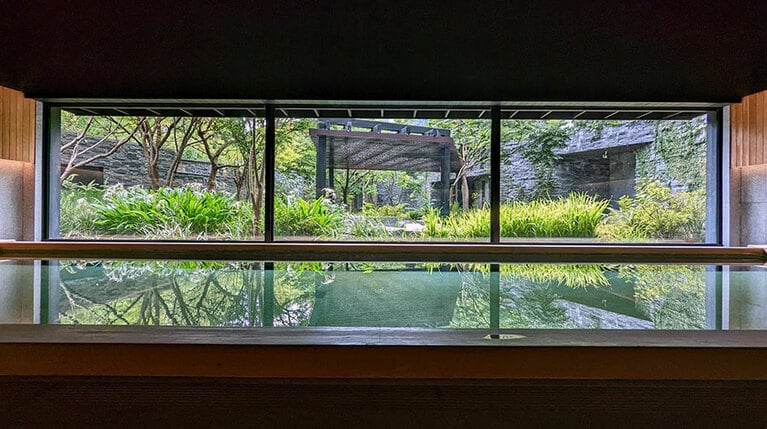 明るく広々とした大浴場。敷地内に植えられた緑はまぶしいほどの美しさです。