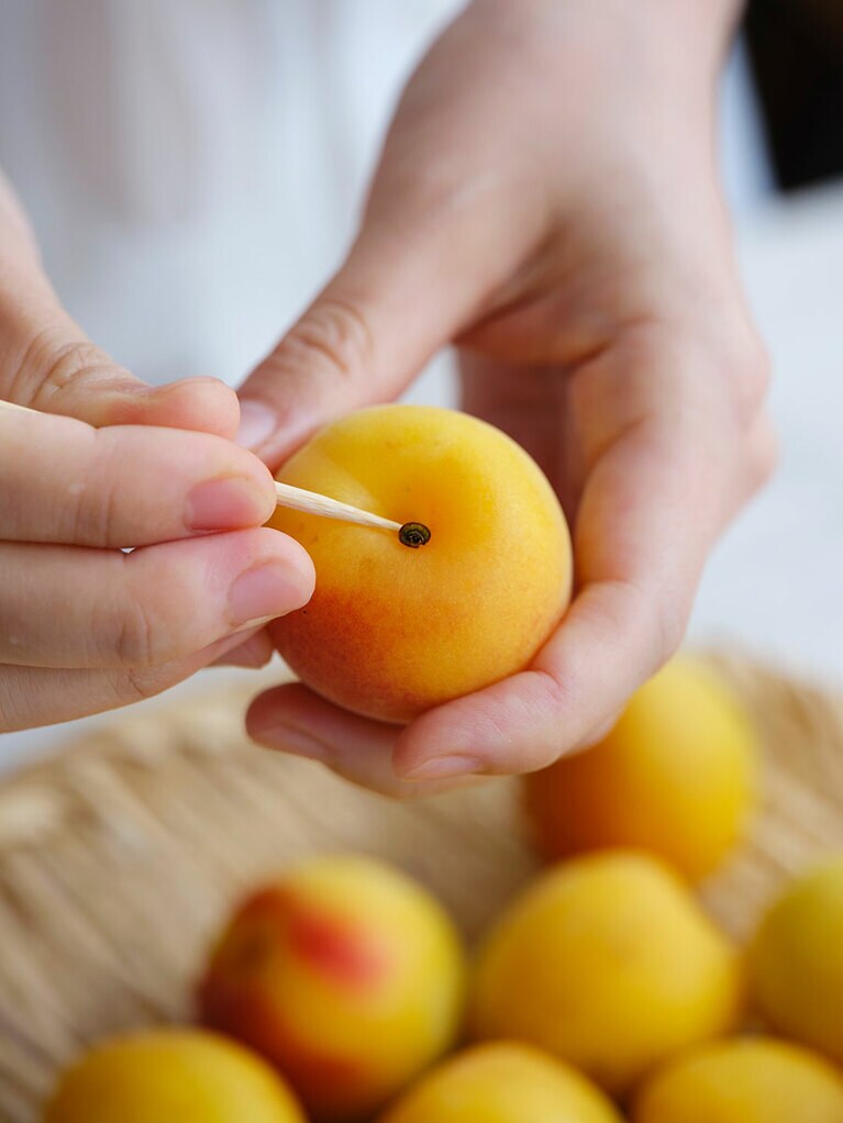 （1）完熟梅はやさしく洗い、水けをペーパータオルでていねいにふき取り、なり口のヘタを竹串で取る。