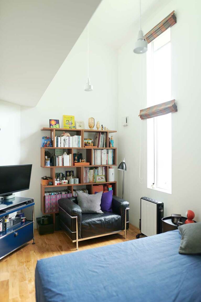 天井の高い寝室。ここにも本棚があり、本やフィギュアがお店のように収められている。この一人がけソファで読書をするのもYさんの日常的な過ごし方。パソコンもテレビもリビングには置かず、この部屋で。