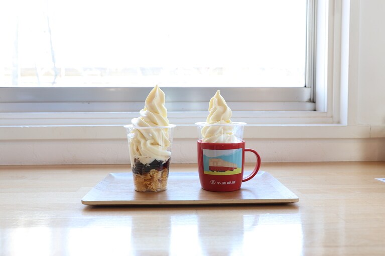左は里山トロッコ機関車をイメージしたコーヒーゼリーの「トロッコパフェ（400円）」。右は「赤コップ付きソフトクリーム（640円）」。
