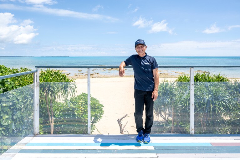 富永五男さん。美しいビーチを一望する「ガジュマルテラス」も手作り。