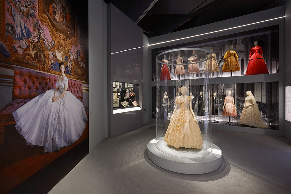 英国におけるディオールの活躍ぶりがわかるギャラリー「Dior in Britain」。中央に展示されているのが、故マーガレット妃が21歳の誕生日に着用したドレス。当時の写真が左側の壁に飾られている。©ADRIEN DIRAND