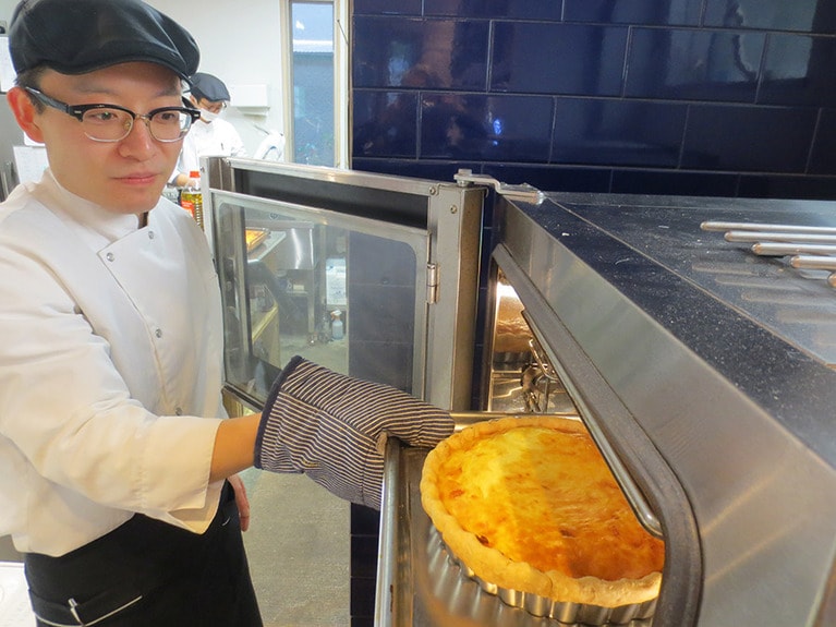 キッシュの焼き上がりをチェックするスタッフ。