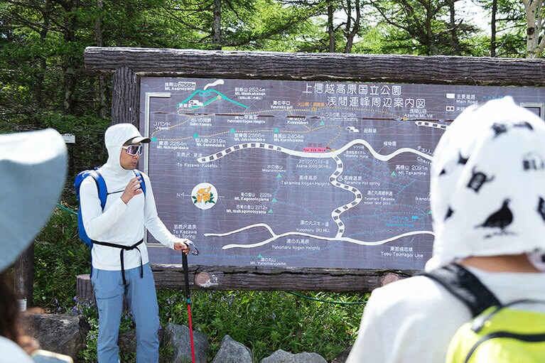 登山口にある浅間連峰の地図を見ながら、ルートを説明してくれるガイドの照井さん。