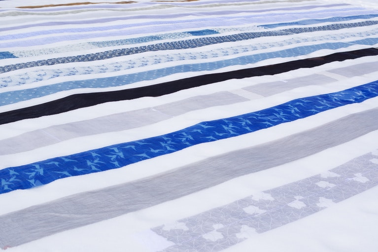 雪の上に次々に並べられていくと太陽に照らされて織物が光って見える。美しい雪国の風景。