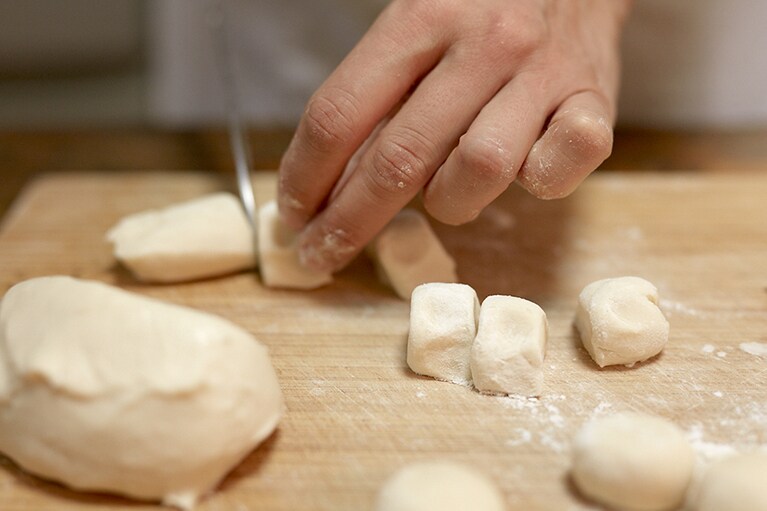 打ち粉(強力粉)をし、幅3cmくらいの棒状にのばし、3cm角になるように切る(1個 約10g)。