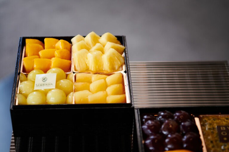 黄金桃、パイナップル、プラム、マスクメロンのドルチェが詰められた一つ目のお重。