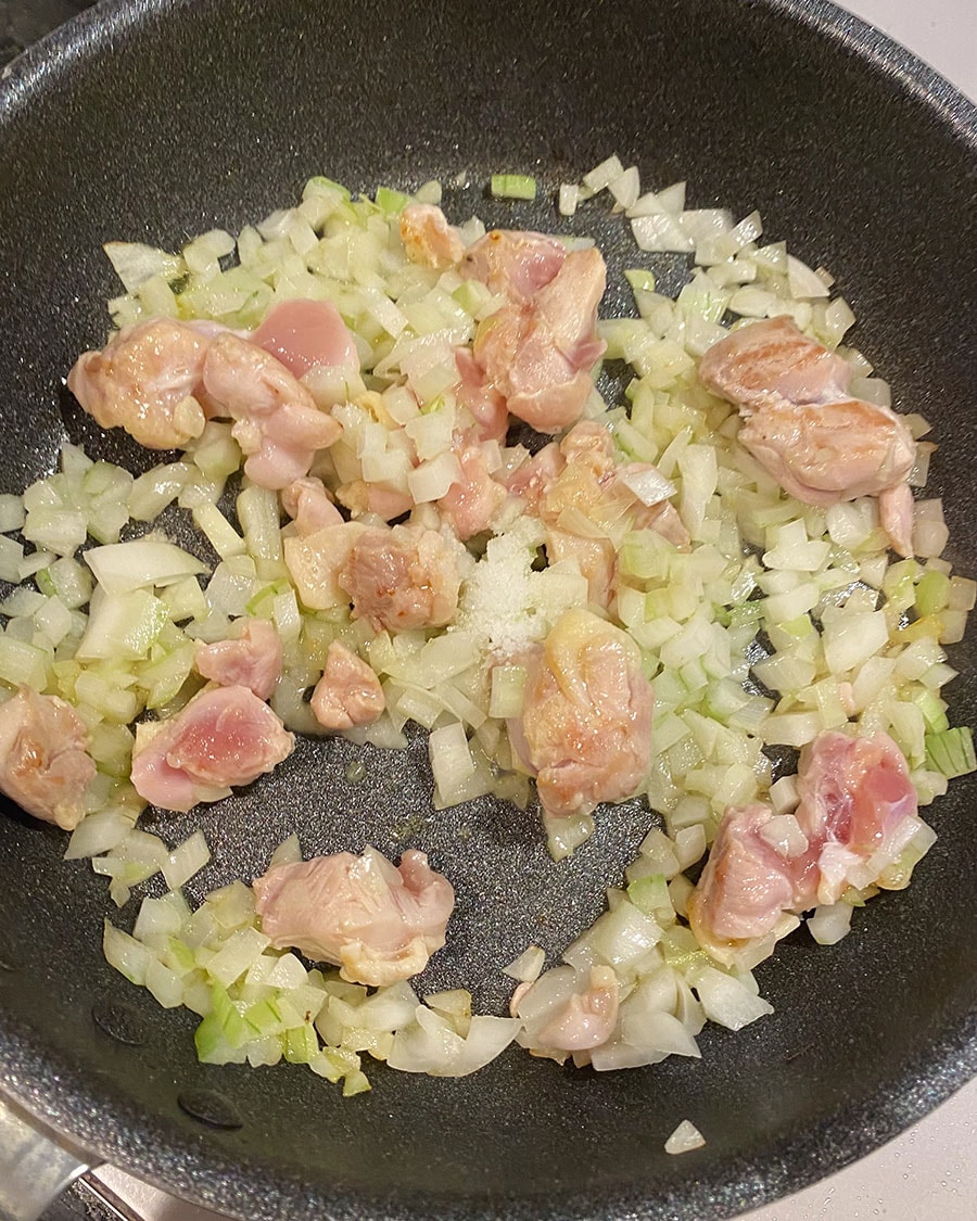 【焦がし醤油のケチャップライスが主役のオムライス】(2) フライパンにオリーブオイルを入れたら火をつけて熱し、鶏肉と玉ねぎを中火で炒める。玉ねぎが透き通ってきたら塩とブラックペッパーを加えてさらに炒める。