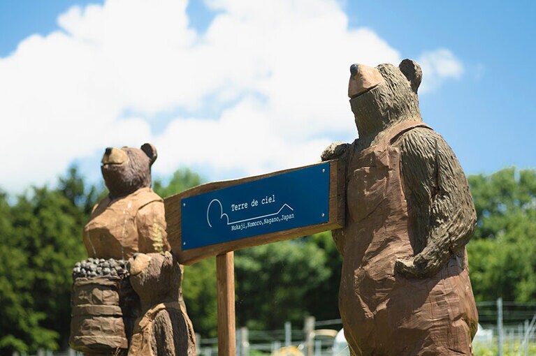 ブドウ畑の入り口には、熊の親子の看板が。この位置から畑を眺めると、遠くに富士山を望める。