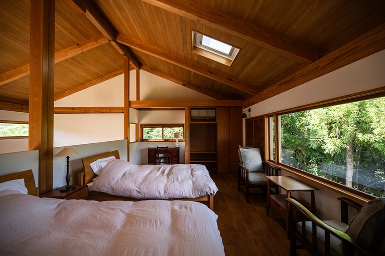 スーペリア・スイートのベッドルーム。大きな窓から広大な木々を望む。