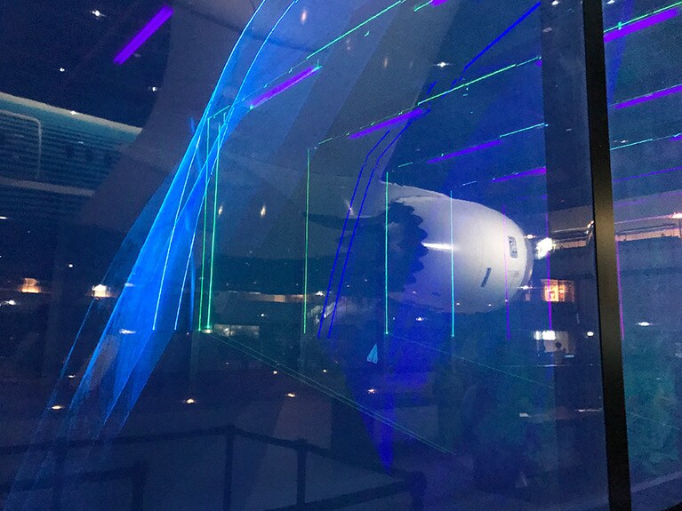 光の層がある部屋で紙飛行機を飛ばすと、光が飛行機に反応して幻想的な光景になる。