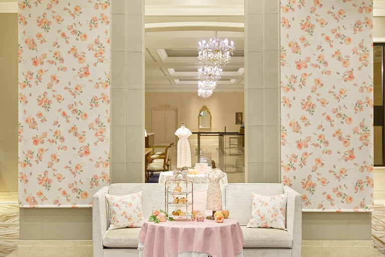 フラワーモチーフとピーチ柄をふんだんに散りばめた『any SiS』のリミテッドプリントワンピース（13,900円・税込）は、『any SiS』全店舗と公式通販サイトで販売中。写真は、「The Lobby Cafe」店内のフォトブース。