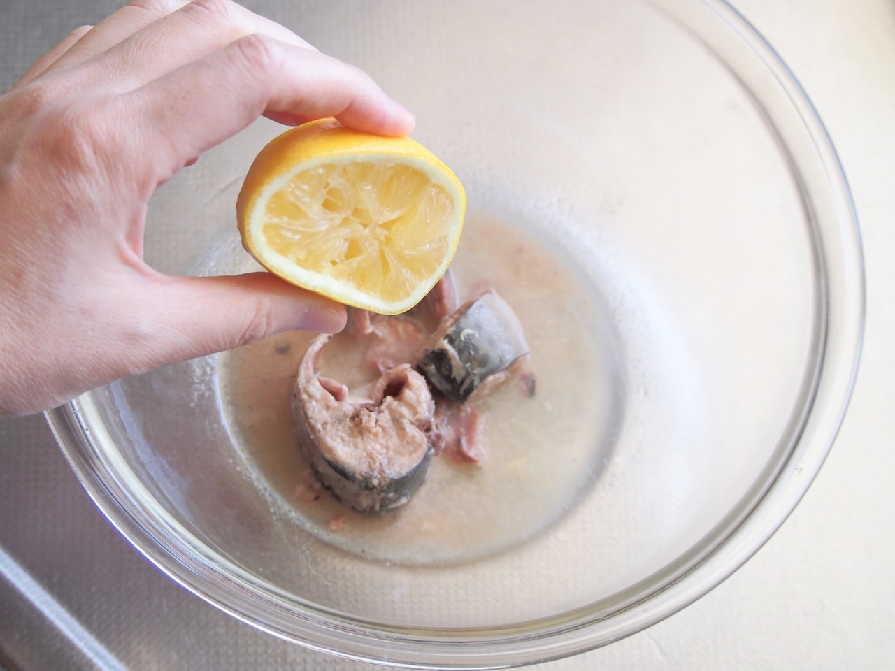 ボウルに鯖缶と、缶の汁大さじ1程度を入れ、レモンを絞り入れる。