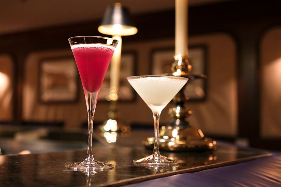 「マリナーズクラブ」の人気カクテル。左から、現在の飛鳥Ⅱ船長の好む日本酒やジュースを用いた“キャプテンズカクテル”1,100円、飛鳥Ⅱオリジナルのジンをベースにパイナップルやミントが香る“ワールドクルーズ”1,650円。