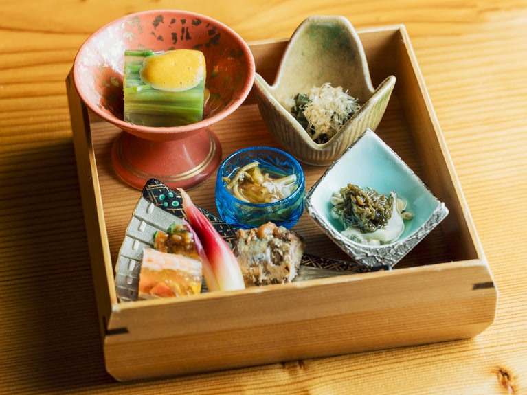 夏のある日の夕食から、前菜の盛り込み。秋田杉の盛器に、蕨のおひたしやミズの煮こごり、ジュンサイの酢の物など山の幸が品よく並ぶ。