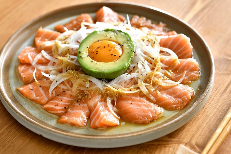 「サーモンの和風アボカド月見カルパッチョ」。アボカドの種の部分に収まった玉子の黄身を崩して玉ねぎと絡めると、ノルウェーサーモンがより豊かな味わいに。